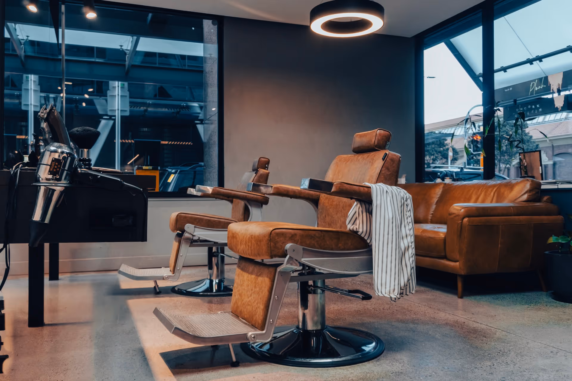 Black wooden sign with a white logo featuring barber tools and a striped barber pole with crown, reading 'RUKU BARBERS'.
